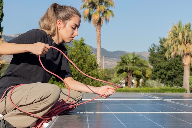 Vue latérale d'une jeune femme électricienne et ingénieur travaillant et réparant les panneaux photovoltaïques