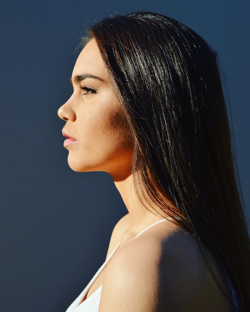 Vue latérale d'une jeune femme sur un fond bleu