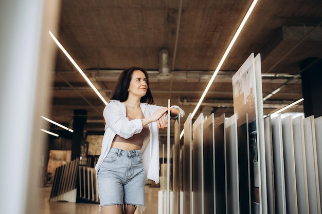 Vue latérale d'une jeune femme joyeuse souriante tout en choisissant de nouveaux carreaux de sol pour sa maison au magasin de carreaux