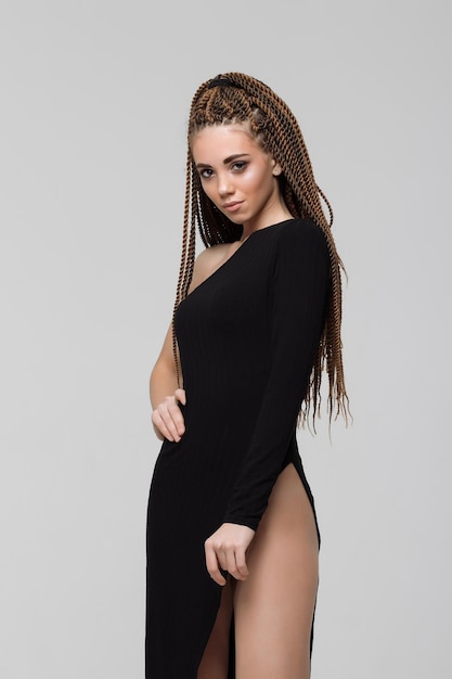 Vue latérale d'une jeune femme sensuelle avec de longues dreadlocks portant une robe noire incroyable