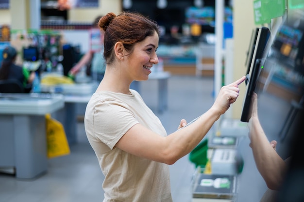 Photo vue latérale d'une jeune femme souriante utilisant un guichet automatique