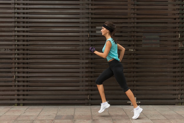 Vue latérale d'une jeune femme sportive qui court sur un trottoir.