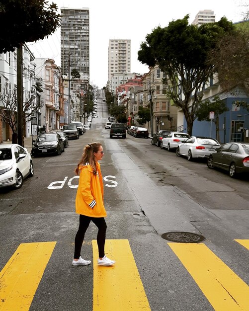 Photo vue latérale d'une jeune femme traversant la route en ville