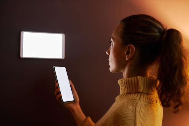 Vue latérale jeune femme utilisant un système de maison intelligente numérique avec des maquettes d'écran