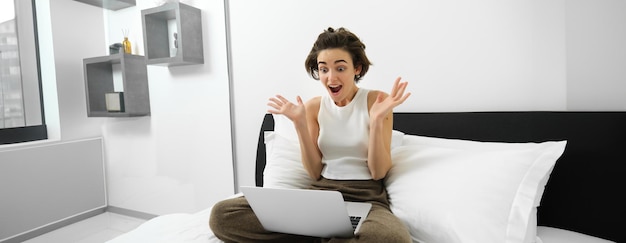 Photo vue latérale d'une jeune femme utilisant un téléphone portable alors qu'elle est assise à la maison