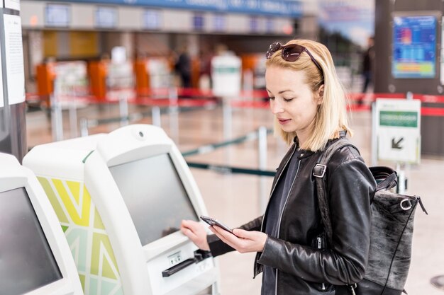 Photo vue latérale d'une jeune femme utilisant un téléphone portable au bureau