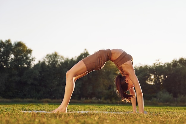 Vue latérale Jeune femme en vêtements de yoga est à l'extérieur sur le terrain