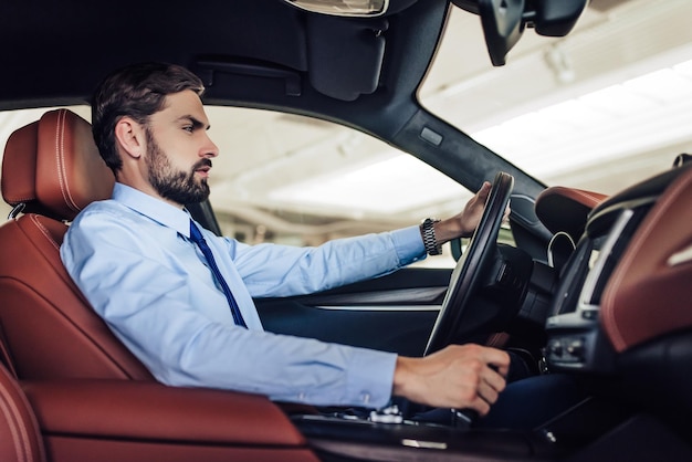 Vue latérale d'un jeune homme d'affaires caucasien conduisant une voiture