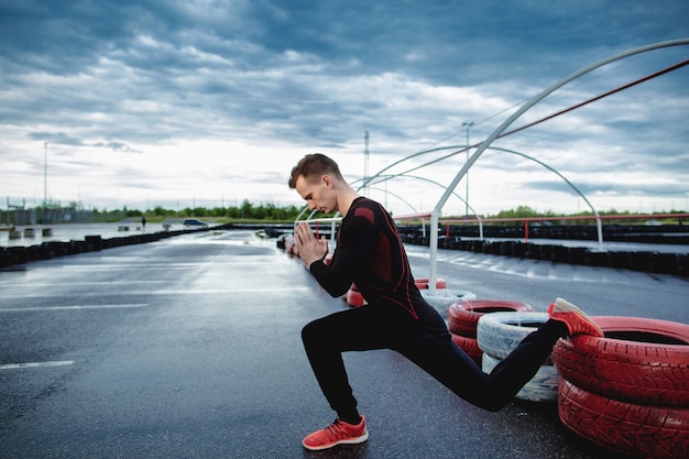 Vue latérale d'un jeune homme athlétique faisant des fentes. Un homme médite à l'extérieur. Yoga, sports de plein air, entraînement