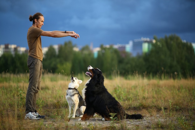 Photo vue latérale à un jeune homme caucasien élégant, formation de deux chiens