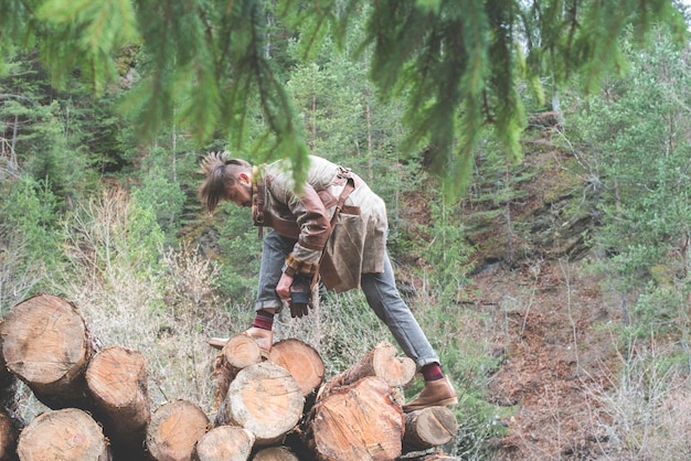 Vue latérale d'un jeune homme debout sur des bûches dans la forêt