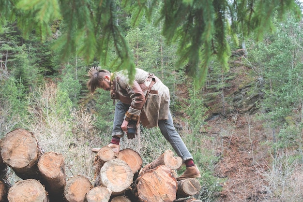 Photo vue latérale d'un jeune homme debout sur des bûches dans la forêt