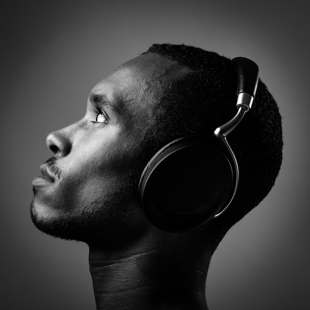 Photo vue latérale d'un jeune homme écoutant de la musique avec des écouteurs sur fond noir