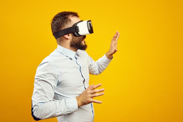 Vue latérale d'un jeune homme portant un casque de réalité virtuelle touchant l'air