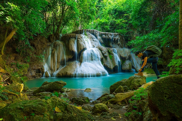 Vue latérale d'un jeune homme avec un sac à dos debout près d'une cascade en forêt