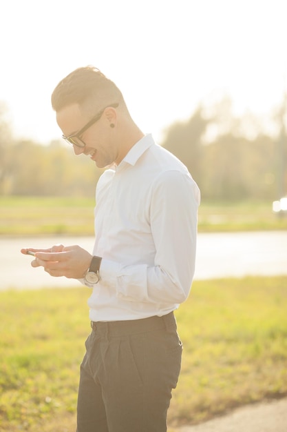 Photo vue latérale d'un jeune homme utilisant un téléphone intelligent alors qu'il se tient dans la ville