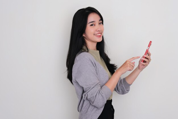 Vue latérale de jeunes femmes asiatiques souriantes en touchant son téléphone portable