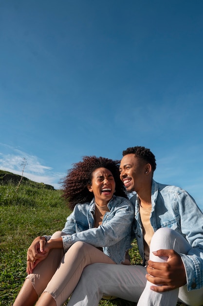 Photo vue latérale joli couple assis à l'extérieur