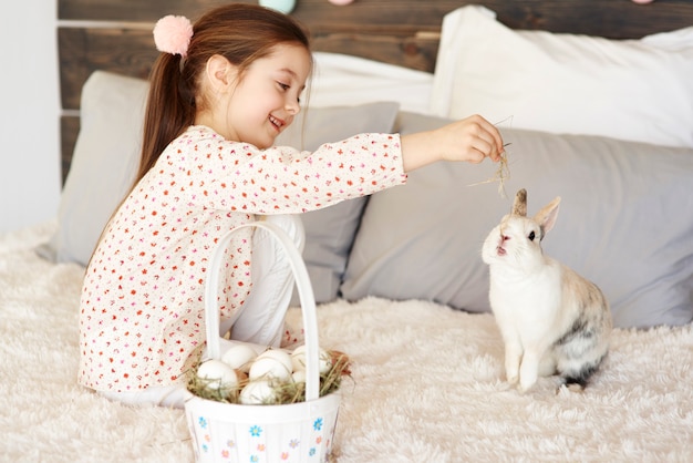 Vue latérale d'une jolie fille nourrissant le lapin