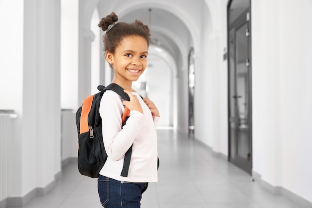 Vue latérale de la jolie petite fille de l'école africaine qui marche à l'école pendant la pause