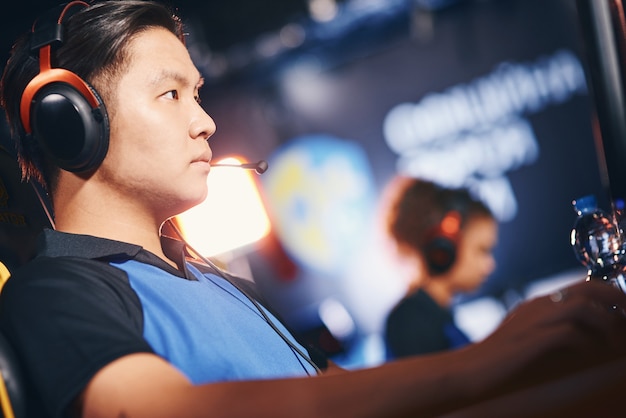 Vue latérale d'un joueur de cyber-sport masculin masculin asiatique portant des écouteurs jouant en ligne