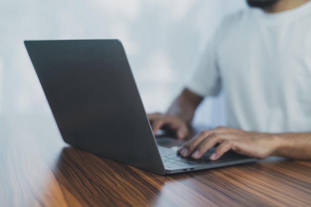 Vue latérale des mains masculines tapant sur le clavier d'un ordinateur portable