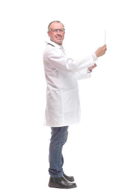 Vue latérale d'un médecin réfléchi portant des lunettes examinant l'image radiographique en se tenant debout, isolé sur blanc