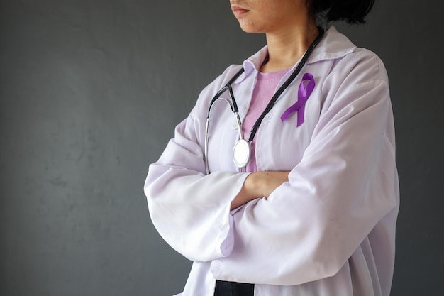 Vue latérale d'une médecin avec un ruban violet sur sa poitrine comme symbole de la Journée mondiale du cancer