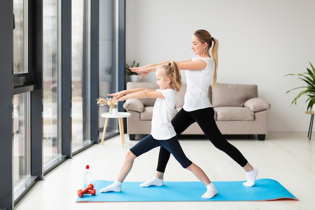 Vue latérale de la mère exerçant avec l'enfant à la maison