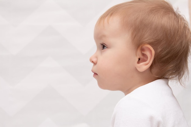 Photo vue latérale d'une mignonne petite fille qui détourne le regard alors qu'elle est assise contre le mur