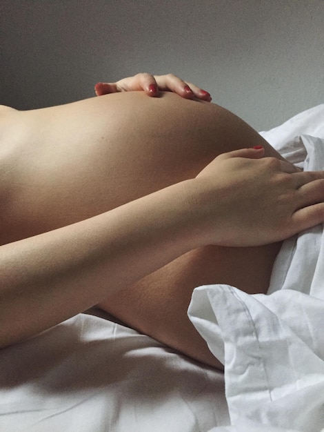 Photo vue latérale de la moitié d'une femme enceinte allongée sur le lit