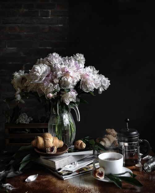 vue latérale nature morte avec un bouquet de fleurs de pivoine sur une table de petit déjeuner sur fond de mur de brique