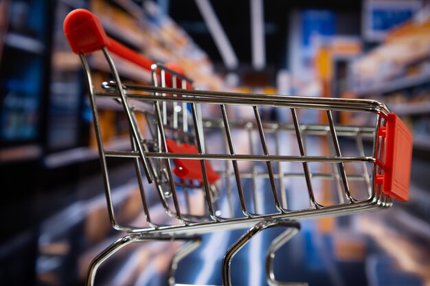 Vue latérale d'un panier d'achat dans un couloir de supermarché en déclin à l'arrière-plan