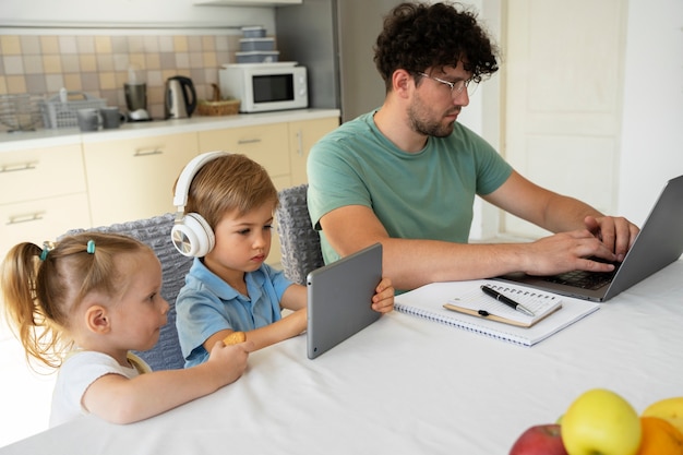 Photo vue latérale père et enfants assis à table