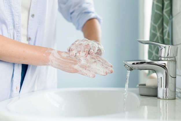 Photo vue latérale d'une personne se lavant les mains dans la salle de bain