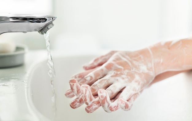 Vue latérale d'une personne se lavant les mains avec du savon et de l'eau