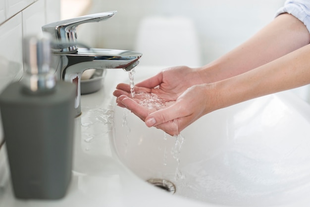 Photo vue latérale d'une personne se rinçant les mains avant de se laver avec du savon