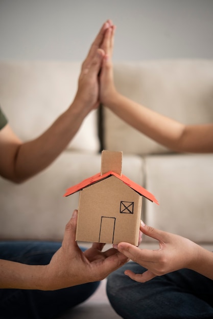 Vue latérale des personnes tenant une petite maison