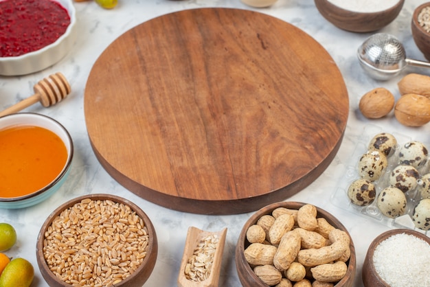 Vue latérale d'une planche de bois ronde parmi des œufs de miel de confiture de farine riz brun sur fond de glace