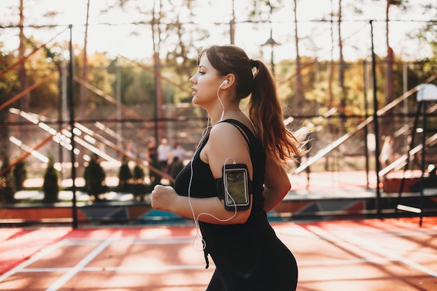 Vue latérale portrait d'une belle femme taille plus courir le matin dans un parc de sport pour perdre du poids.