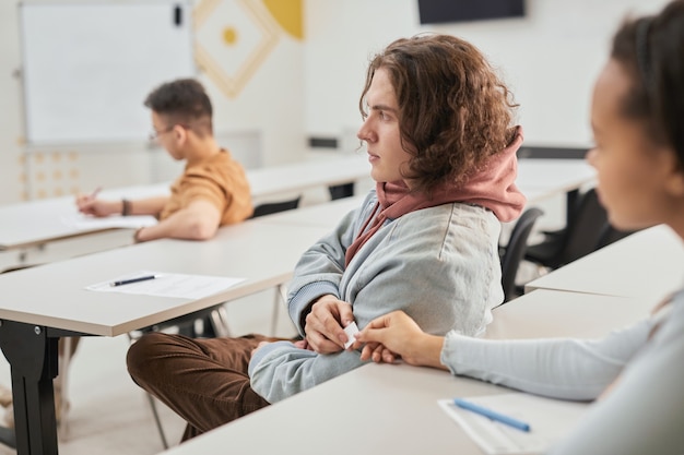 Vue latérale portrait de deux adolescents passant une note en classe pendant la leçon d'école, espace de copie