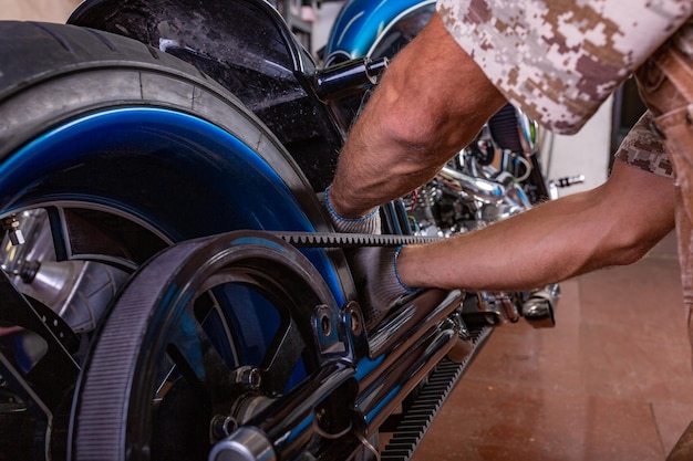 Vue latérale portrait d'un homme travaillant dans un garage réparant une moto. Les mains se bouchent