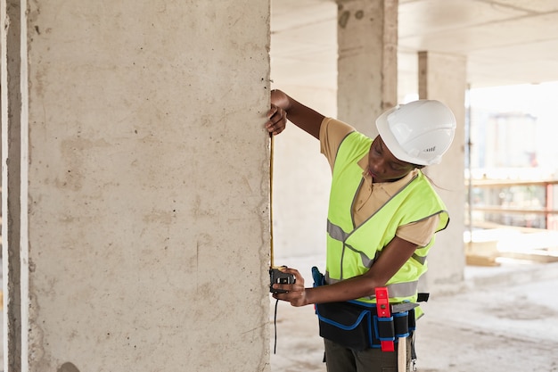 Vue latérale portrait d'une jeune femme afro-américaine travaillant dans un espace de copie de chantier de construction