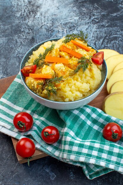 Vue latérale de la purée de pommes de terre servie avec de l'aneth et des légumes frais sur une serviette verte sur une planche de bois sur fond de couleur sombre