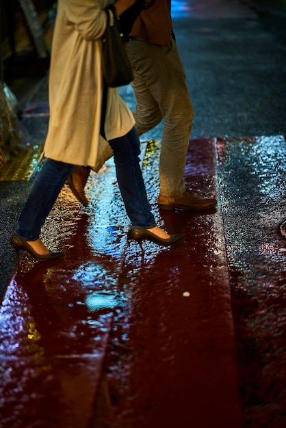 Vue latérale de la section basse d'un couple marchant dans la rue pendant la saison des pluies