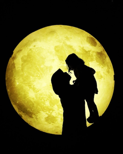 Photo vue latérale de la silhouette d'une personne tenant la lune contre le ciel la nuit