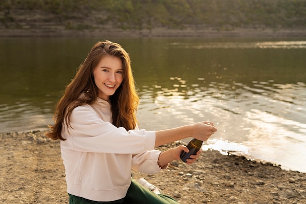 Photo vue latérale smiley femme tenant une bouteille