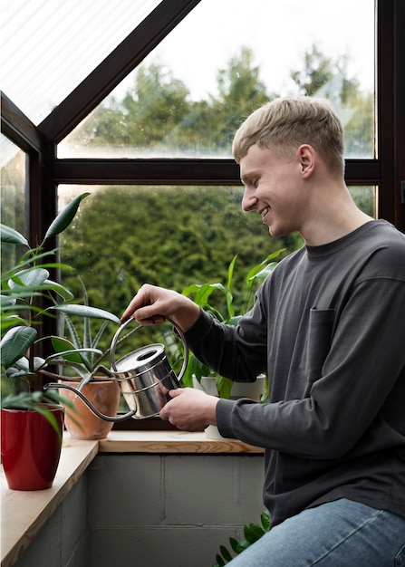 Vue latérale smiley homme arrosant la plante