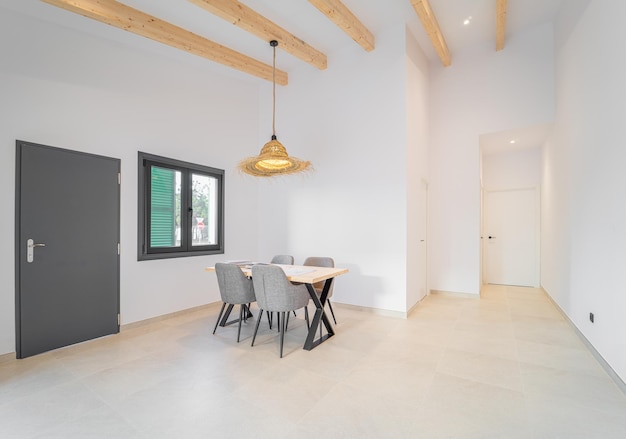 Vue latérale d'une table de salon en bois avec quatre chaises devant la fenêtre du salon