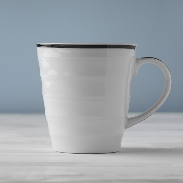 Vue latérale d'une tasse blanche vierge sur tableau blanc et fond bleu